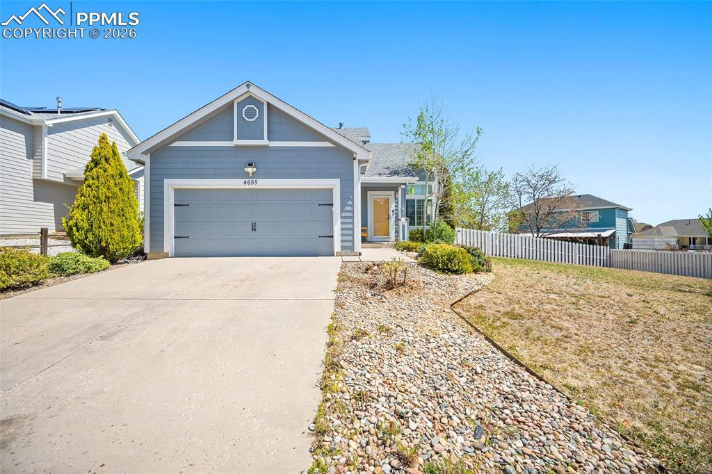 Caption: Single-story residence featuring light blue siding and a light gray garage door with decorative hard