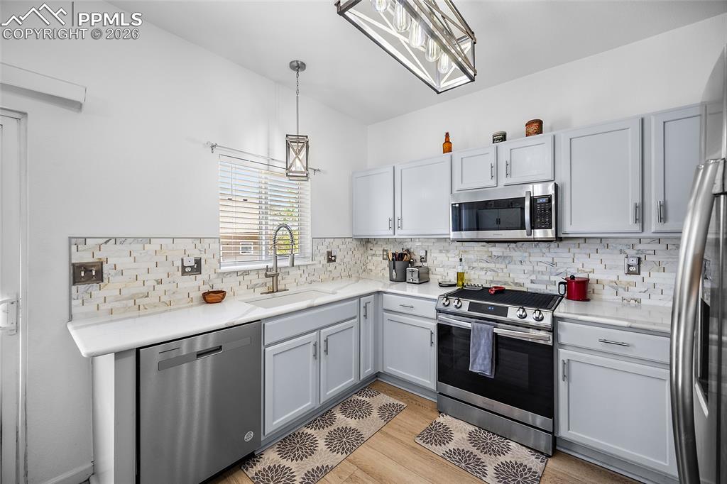 Image 11 of 46: Modern kitchen featuring light gray cabinetry, white countertops, stainless
