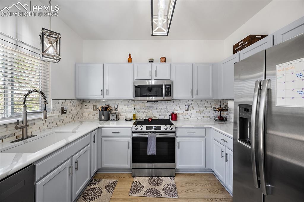Image 15 of 46: Kitchen featuring light gray cabinetry, white countertops, tile backsplash,