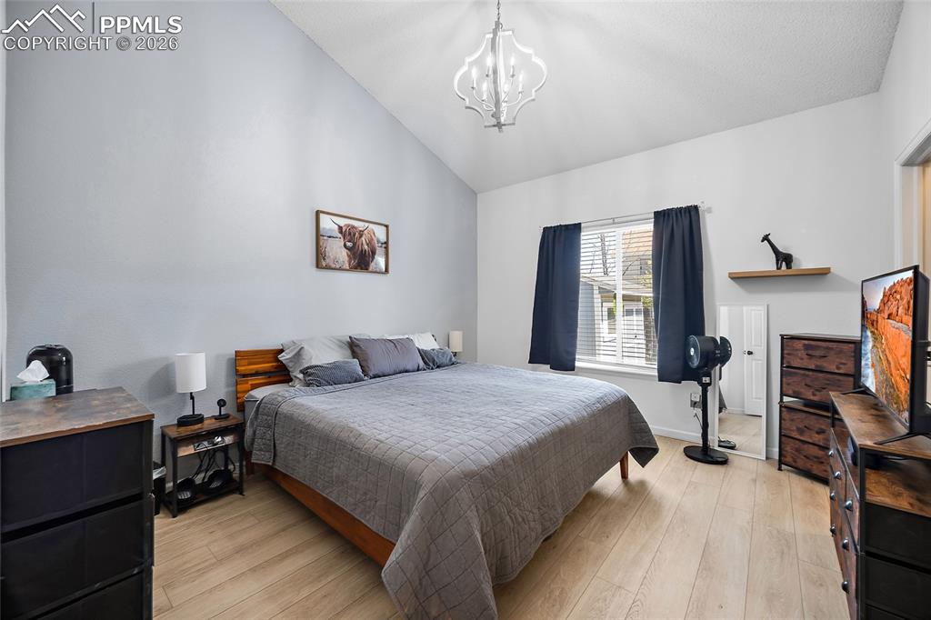 Image 16 of 46: Vaulted ceiling bedroom featuring wood-finish flooring, a contemporary chan