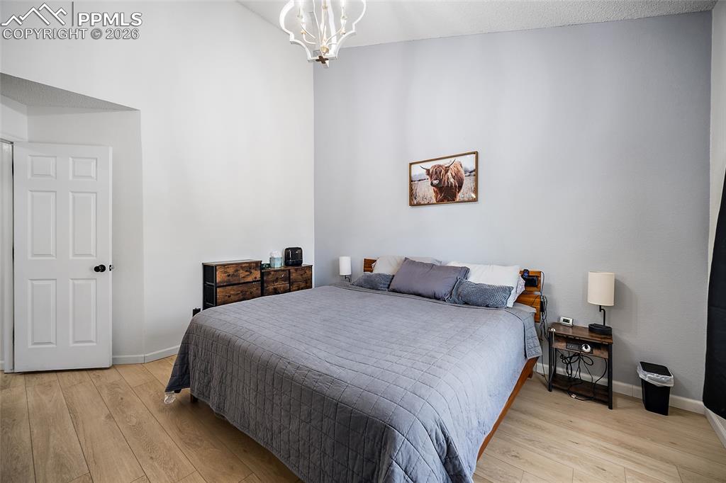 Image 17 of 46: Spacious room featuring wood-finish flooring, a white six-panel door, and a