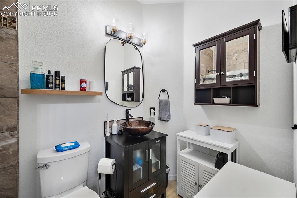 Image 19 of 46: Bathroom featuring a vessel sink with dark wood-finish vanity, wall-mounted