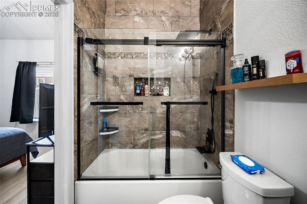 Image 20 of 46: Bathtub and shower combination featuring a glass enclosure with matte black