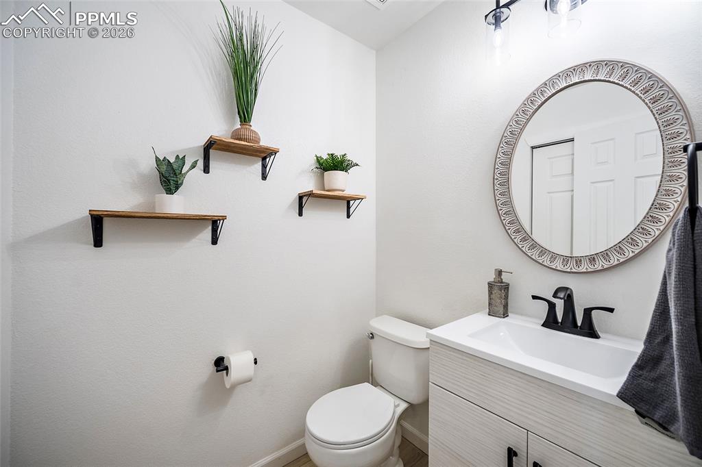 Image 22 of 46: Powder room featuring a white vanity with integrated sink, black faucet, an