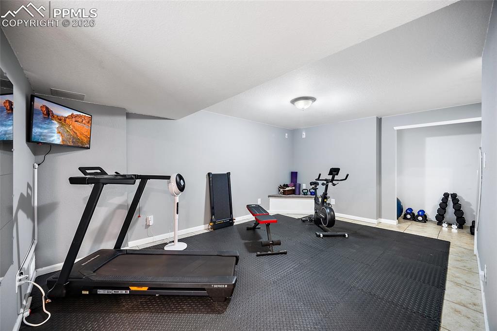 Image 24 of 46: Dedicated fitness area featuring durable rubber mat flooring and neutral gr