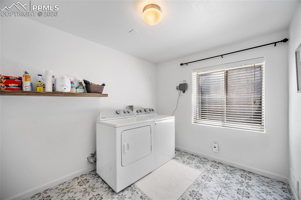 Image 26 of 46: Laundry area featuring patterned floor tile, a floating wood-finish shelf, 