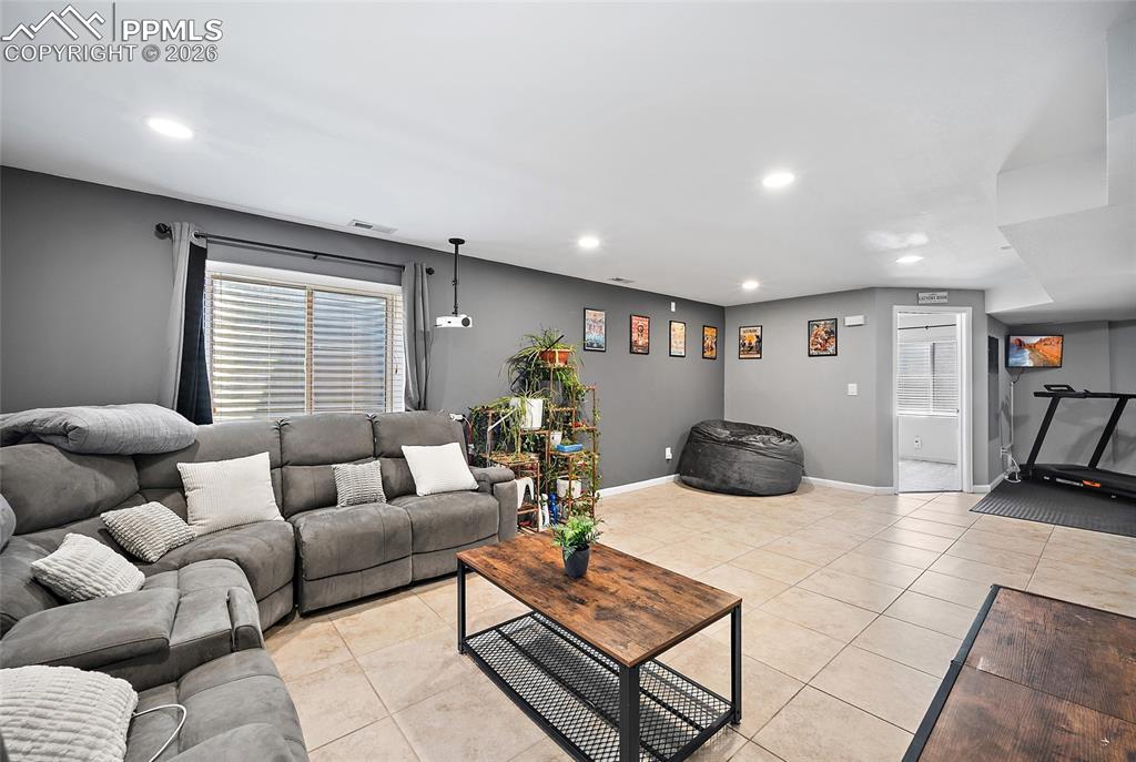 Image 30 of 46: Spacious lower-level room featuring light-toned tile flooring, recessed lig