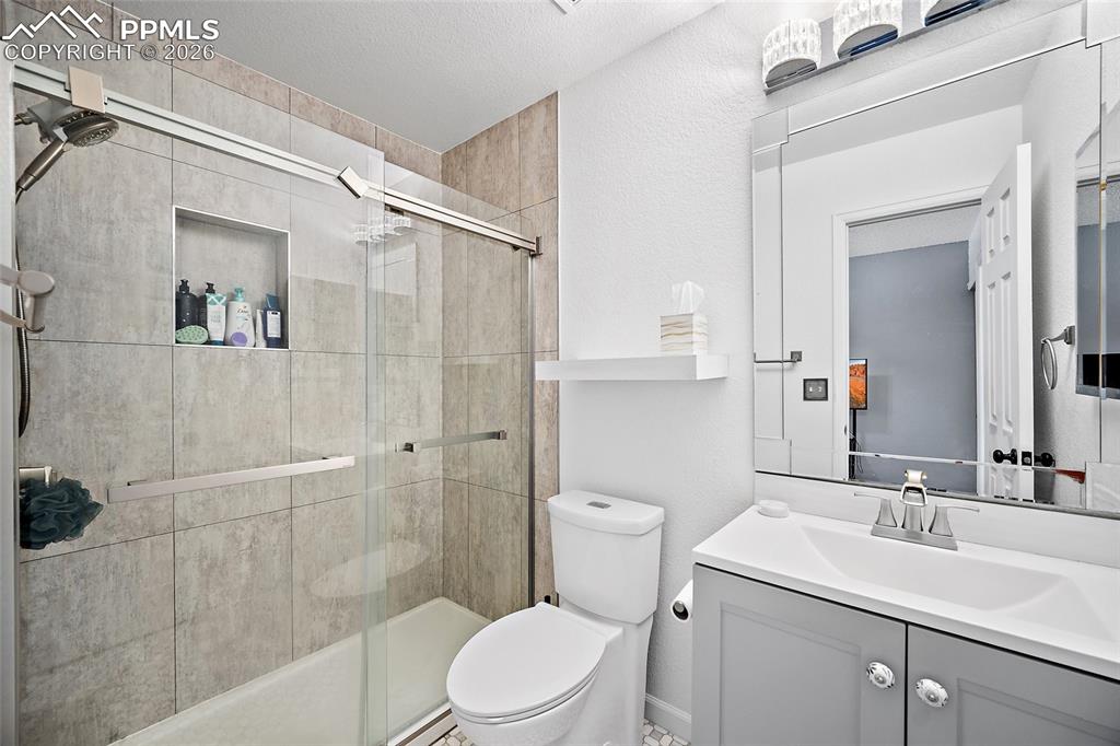 Image 36 of 46: Bathroom featuring a tile-surround tub/shower with sliding glass doors and 
