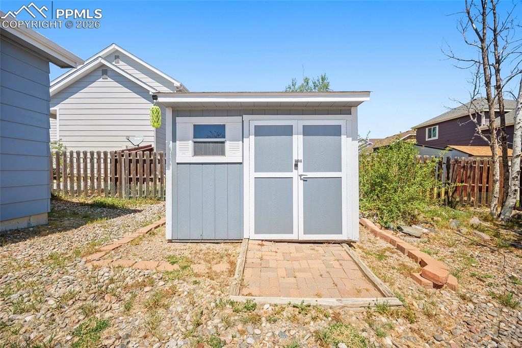 Image 39 of 46: Detached storage shed featuring a pitched roof, light blue siding, white wi