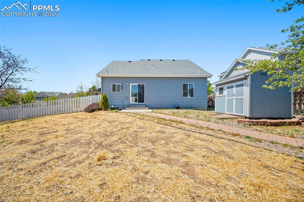 Image 41 of 46: Rear exterior featuring a sliding glass door, a separate utility shed, a wh