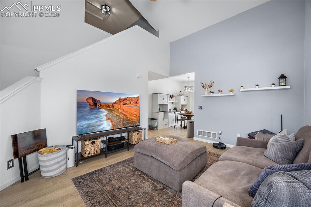 Image 7 of 46: Living room featuring vaulted ceilings, light wood-finish flooring, and whi