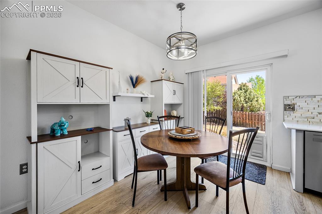 Image 9 of 46: Dining area with wood-finish flooring and a contemporary drum pendant light