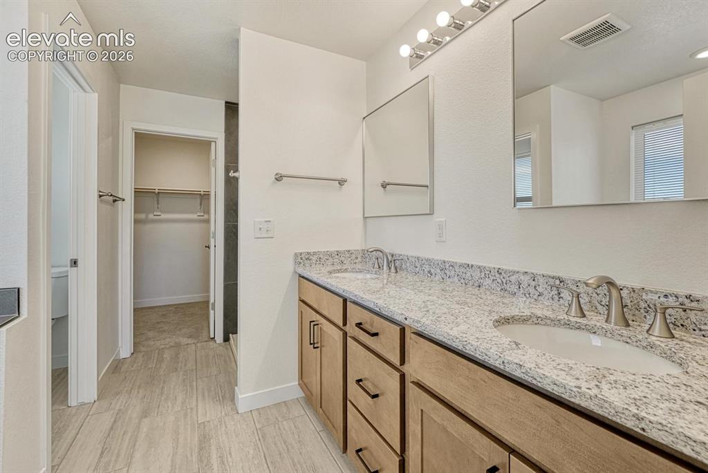 Image 23 of 50: Attached 5-piece primary bathroom with granite counter and undermount sinks