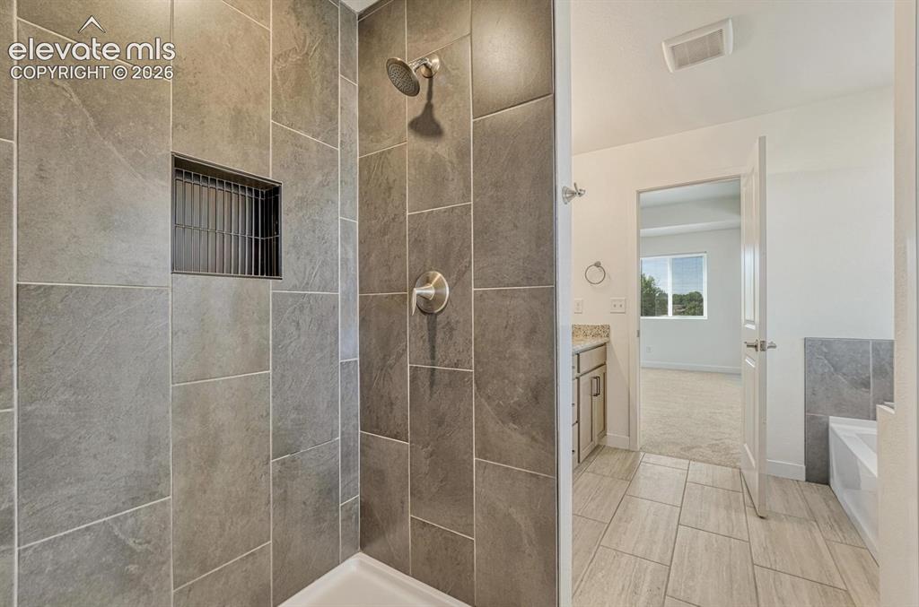 Image 25 of 50: Walk-in shower with floor-to-ceiling tile surround
