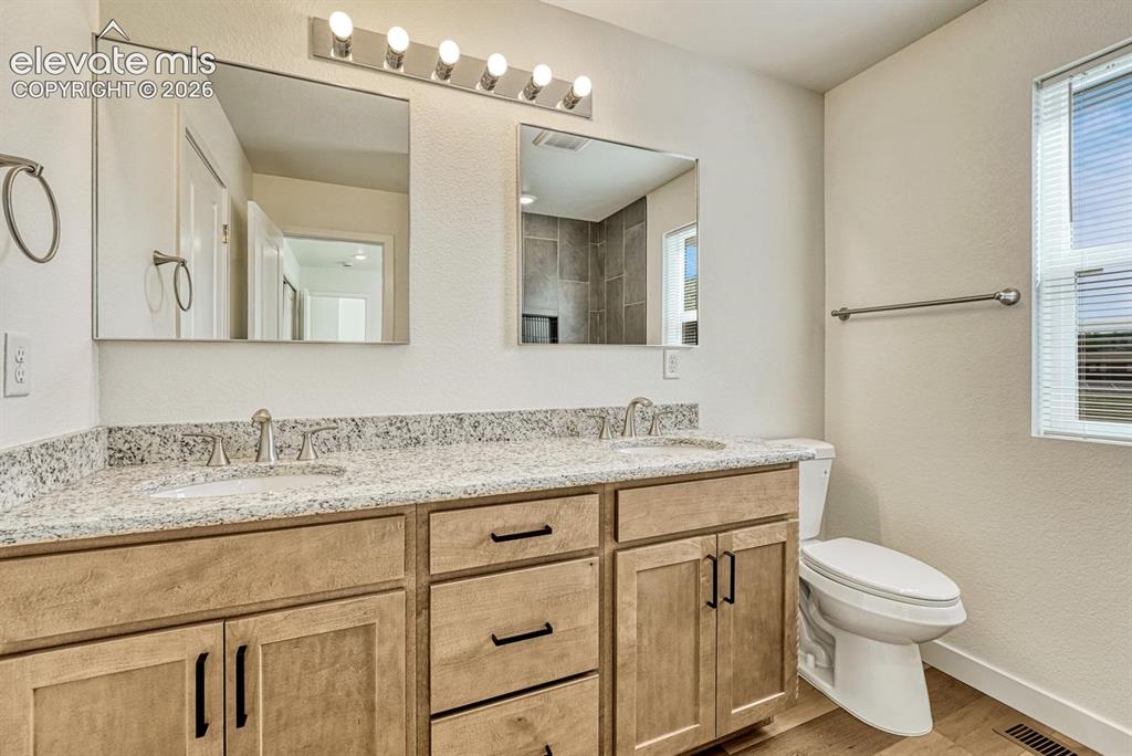 Image 30 of 50: Jack-and-Jill bathroom with double vanity, granite counter, and undermount
