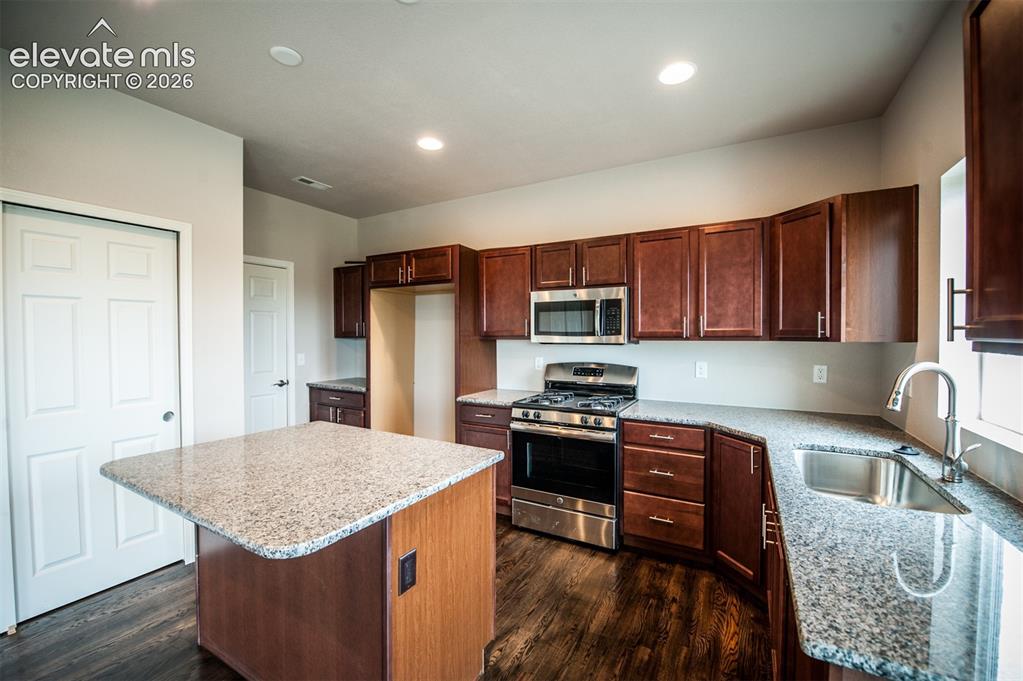 Image 6 of 29: Kitchen featuring island, granite counters, pantry, and stainless appliance
