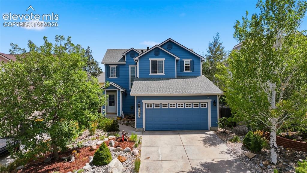 Caption: Two-story exterior with blue siding, a two-car garage, and a concrete driveway