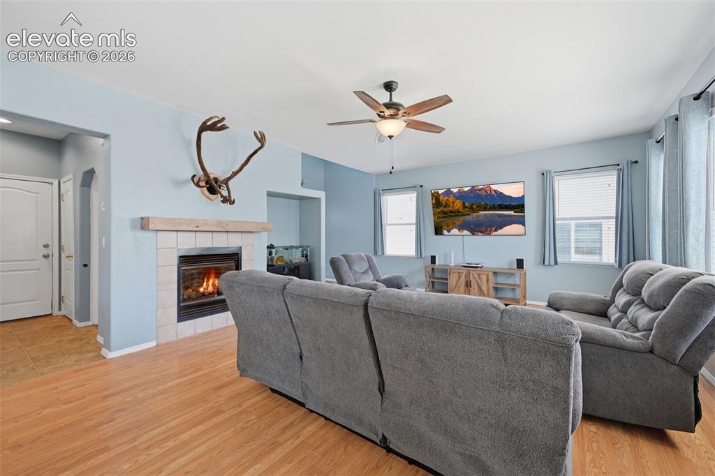 Image 10 of 35: Living space featuring wood-finish flooring, a tiled fireplace with a wood