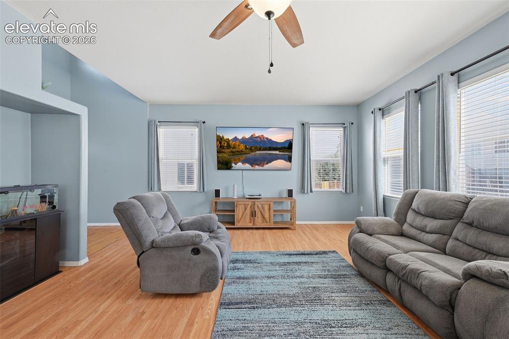 Image 11 of 35: Open-concept living area featuring wood-finish flooring, multiple windows,