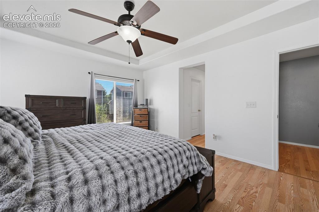 Image 21 of 35: Tray ceiling with a ceiling fan, wood-finish flooring, sliding glass door w