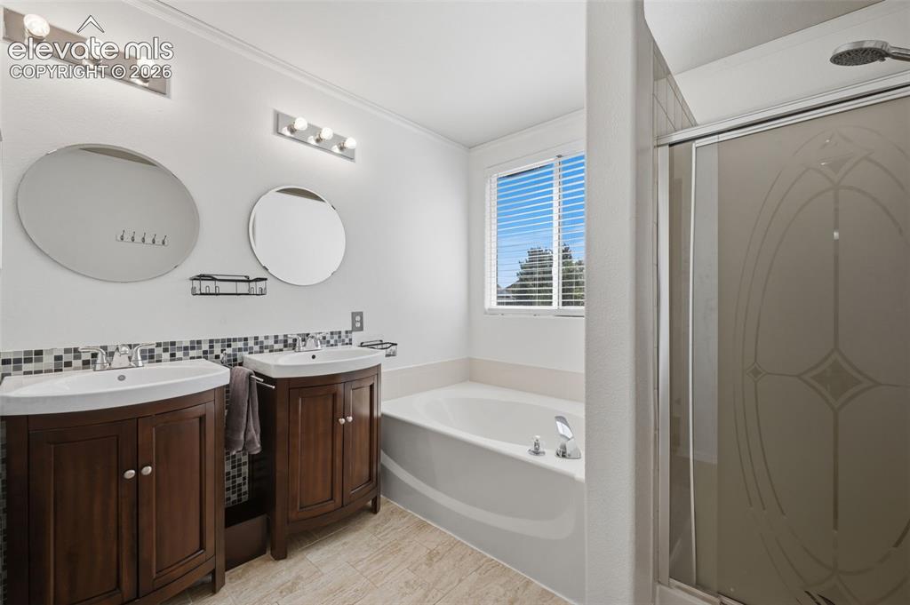 Image 22 of 35: Dual wood-finish vanities with vessel sinks, a jetted soaking tub, tiled fl