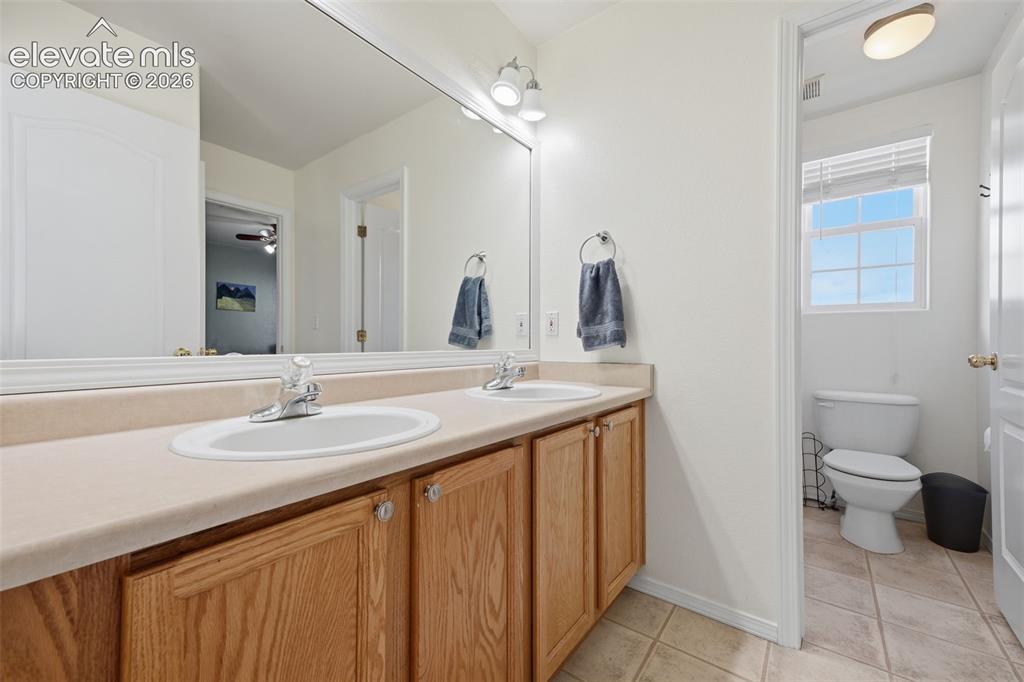 Image 26 of 35: Double vanity with wood-finish cabinetry, chrome fixtures, and a large wall