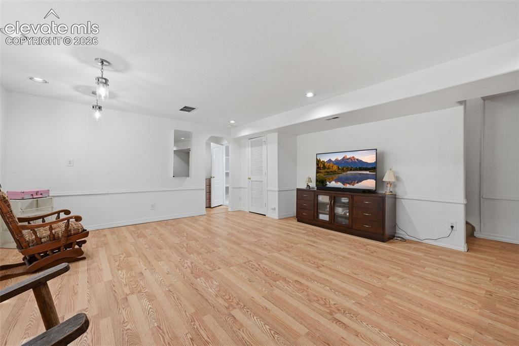 Image 31 of 35: Open-concept living space with wood-finish flooring, recessed lighting, and