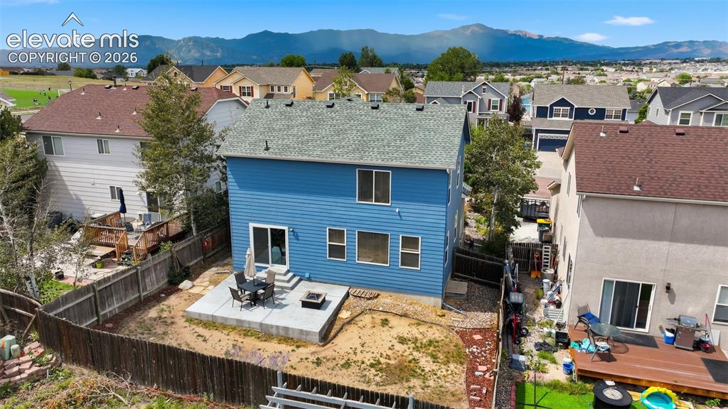 Image 5 of 35: Rear exterior with blue siding, a sliding glass door, multiple windows, and
