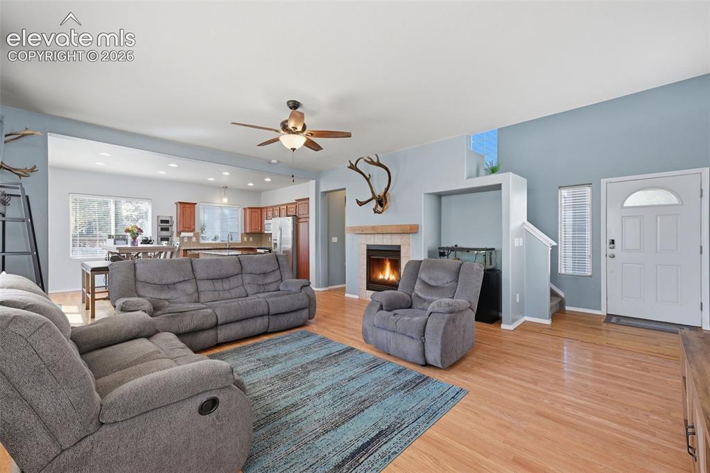 Image 7 of 35: Hardwood flooring throughout, a gas fireplace with a wood mantel, a ceiling