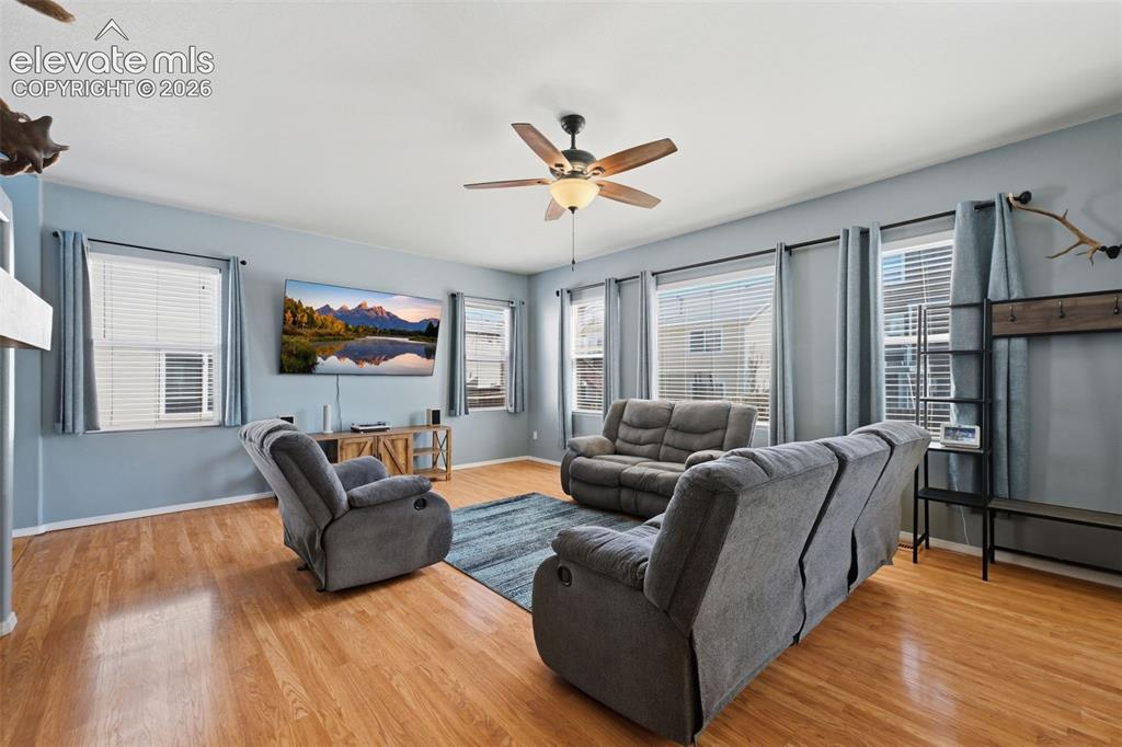 Image 9 of 35: Hardwood-finish flooring, multiple windows with blinds, ceiling fan with in