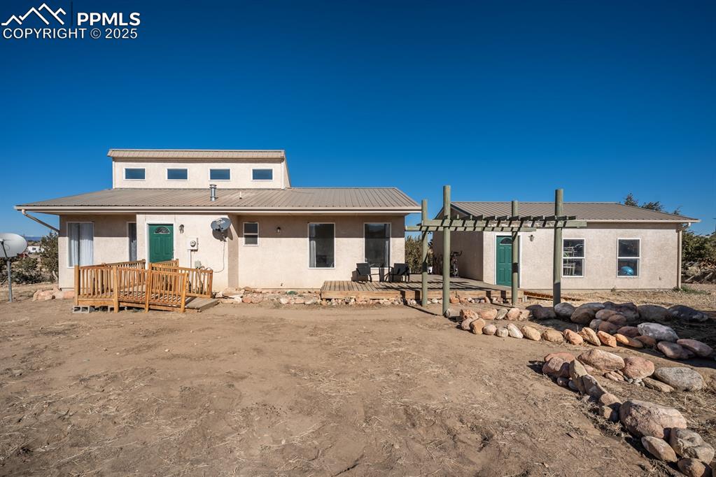 Caption: View of front of house with stucco siding, a metal roof, and a patio