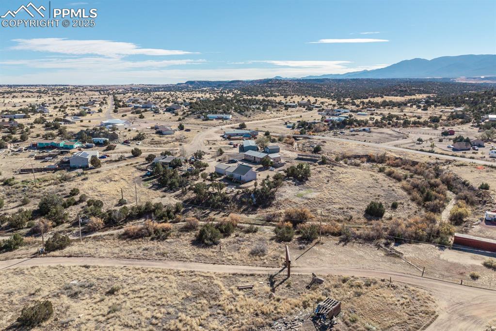 Image 12 of 50: Aerial view of sparsely populated area featuring a desert landscape and mou