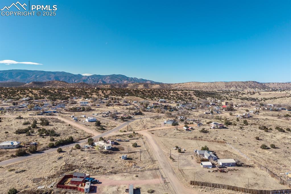 Image 25 of 50: Aerial view of sparsely populated area featuring a mountain backdrop and a