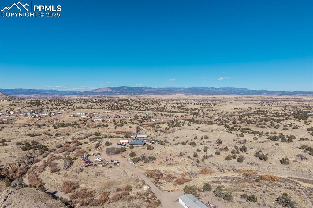 Image 27 of 50: Aerial view of sparsely populated area with a mountain backdrop and a deser