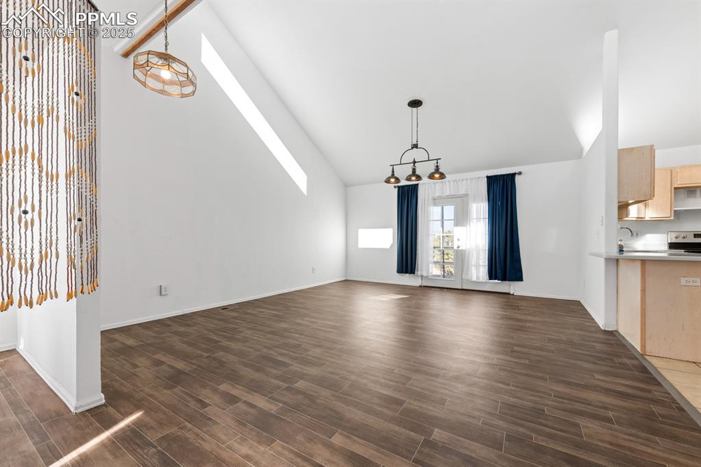Image 35 of 50: Unfurnished dining area with high vaulted ceiling, dark wood-style floors,