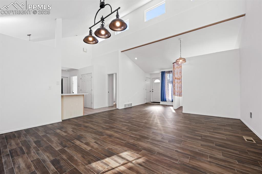 Image 36 of 50: Unfurnished living room featuring high vaulted ceiling and dark wood-style