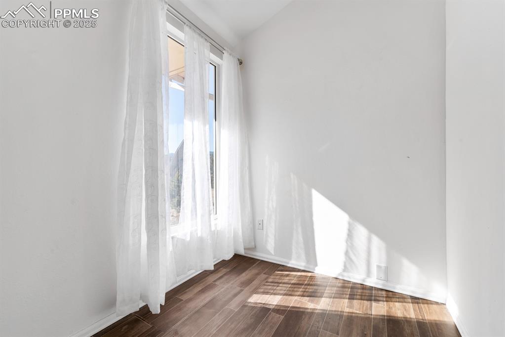 Image 37 of 50: Empty room with dark wood-style floors and lofted ceiling