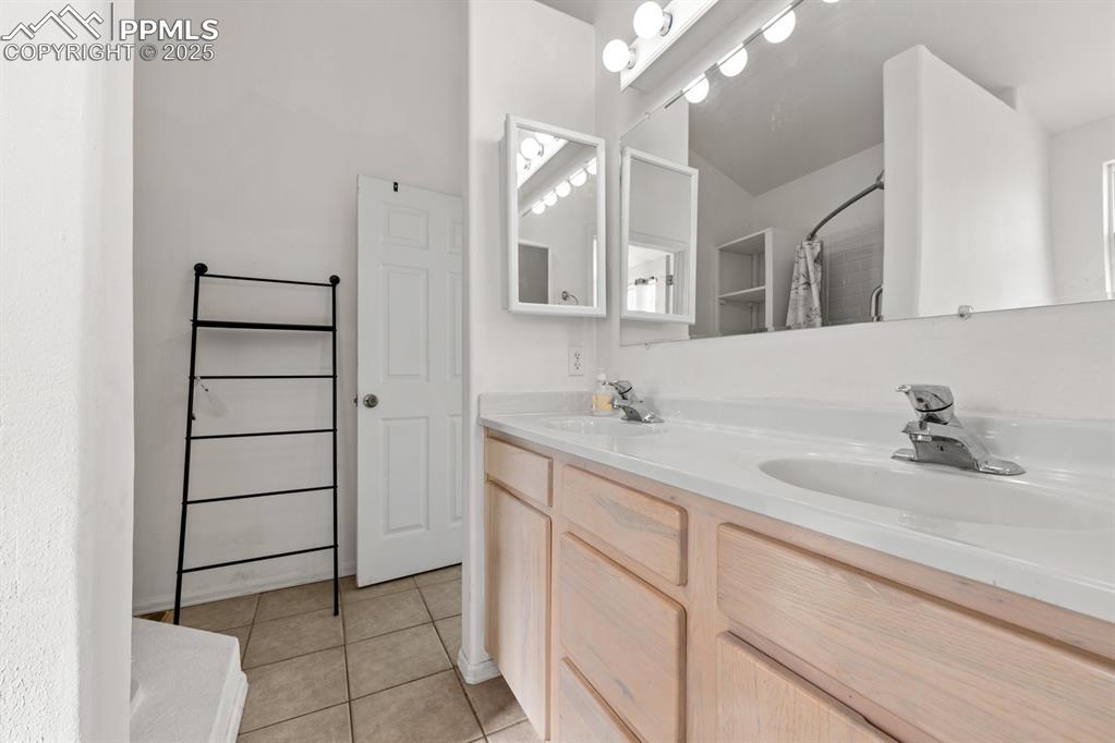 Image 44 of 50: Full bath featuring double vanity, a shower with curtain, and light tile pa