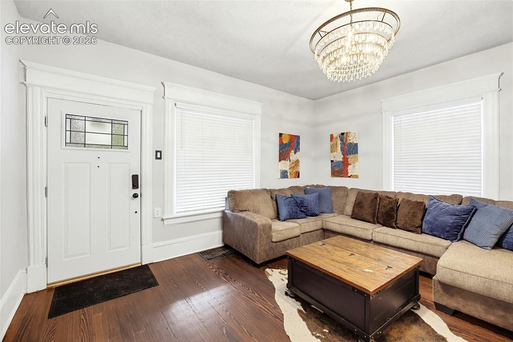 Image 13 of 50: Rich wood-finish flooring, a white paneled entry door with leaded glass, an