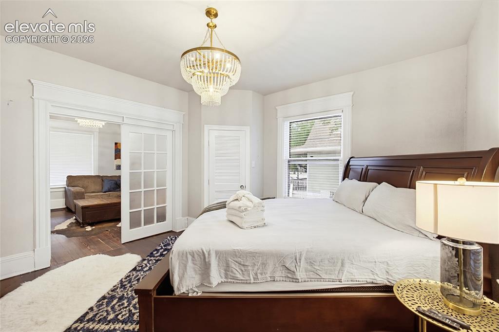 Image 18 of 50: Dark wood-finish flooring, white trim details, window with blinds, and clea