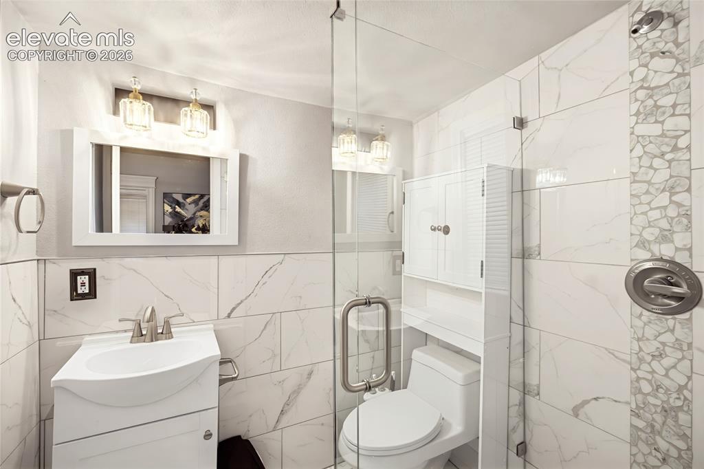 Image 19 of 50: Bathroom featuring a walk-in shower with clear glass enclosure, white recta