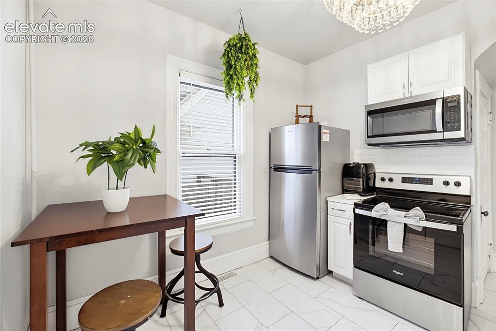 Image 24 of 50: Kitchen featuring stainless steel appliances, white subway tile backsplash,
