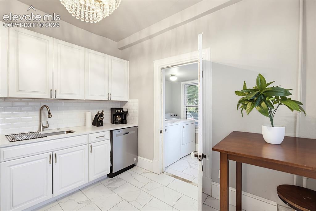 Image 25 of 50: Kitchen featuring white cabinetry, subway tile backsplash, stainless steel