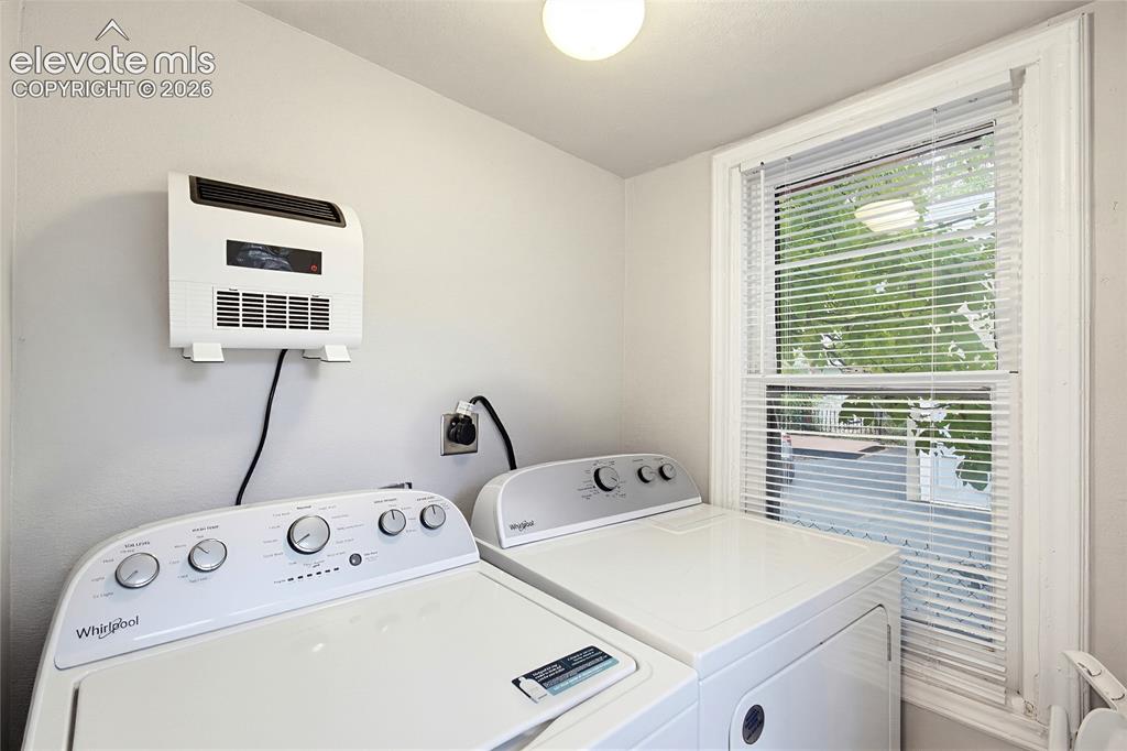 Image 27 of 50: Window with blinds, wall-mounted heater, and ceiling-mounted light fixture