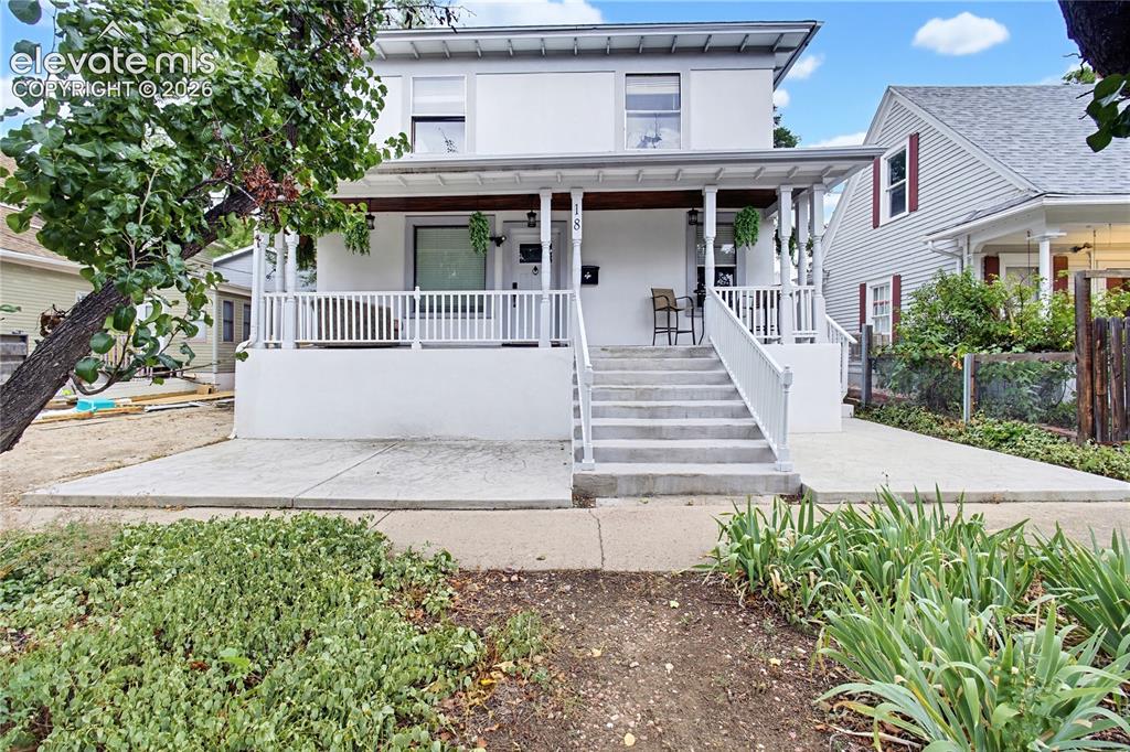 Image 3 of 50: Two-story facade with a covered porch, white railing, and exterior staircas