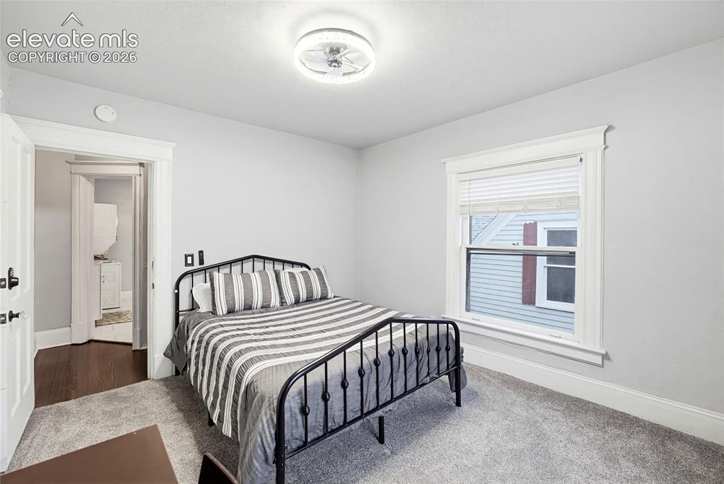 Image 33 of 50: Light gray wall color, carpeted flooring, white trim details, window with w