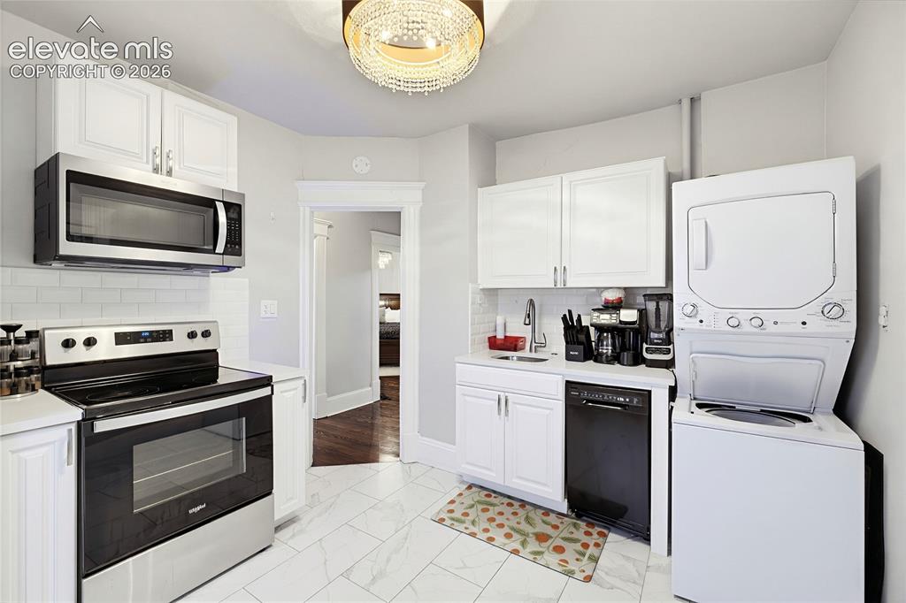 Image 35 of 50: Kitchen featuring white cabinetry, stainless steel appliances, white subway