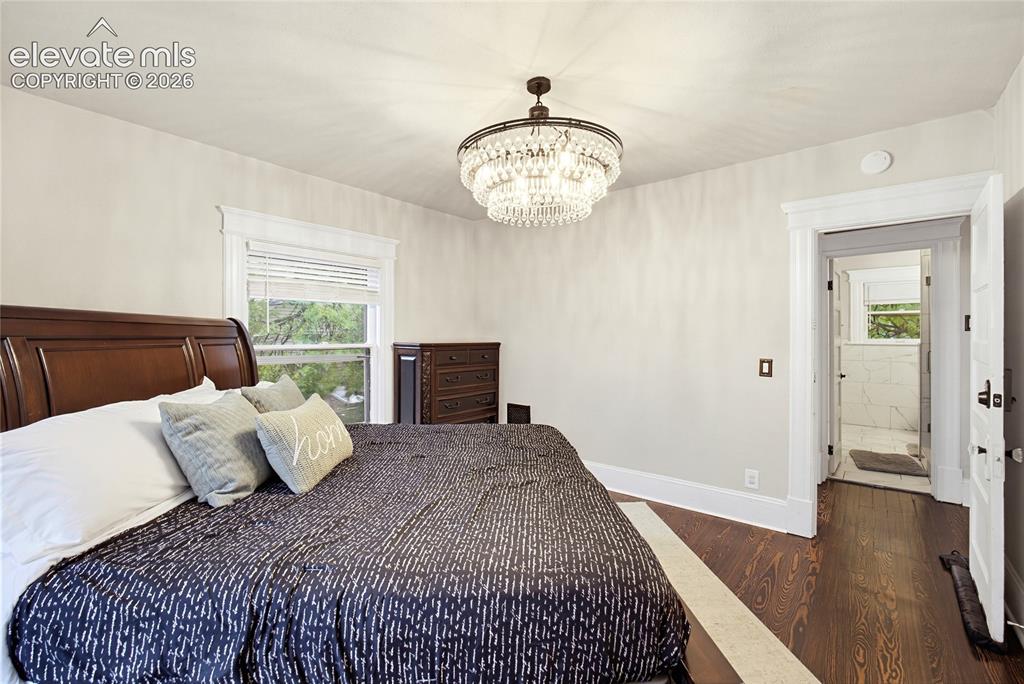 Image 38 of 50: Hardwood flooring, elegant crystal chandelier, window with white blinds, an