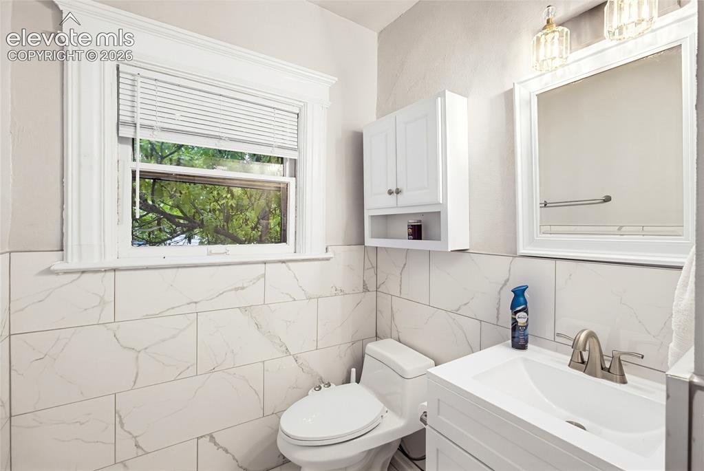 Image 39 of 50: White subway tile with gray veining, white framed window, wall-mounted cabi