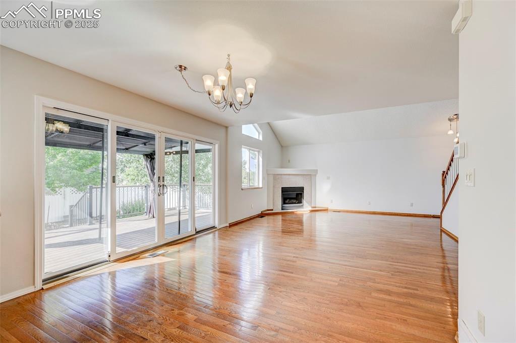 Image 11 of 34: Unfurnished living room with light wood-style floors, a chandelier, vaulted
